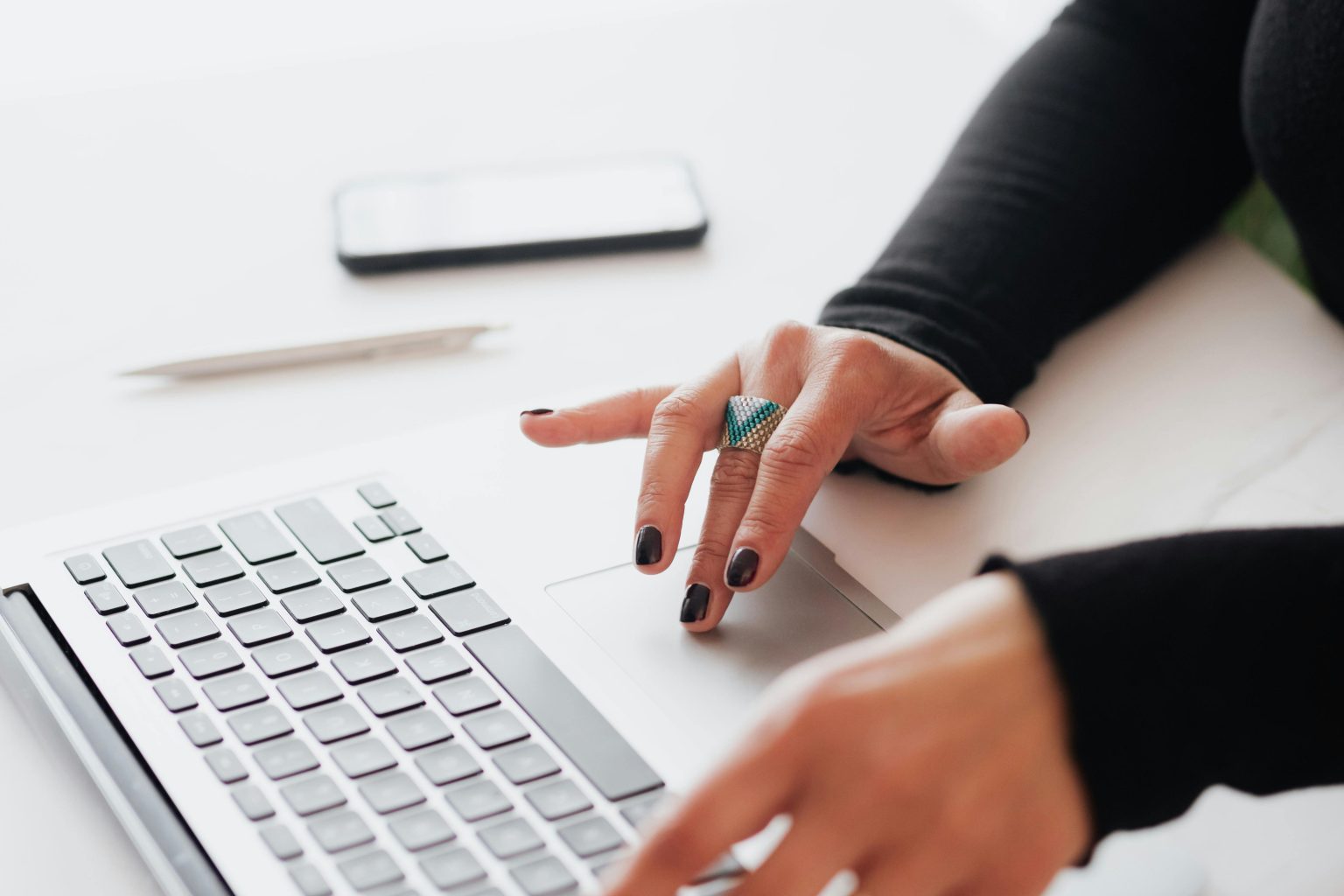 Nahaufnahme einer Person, die fokussiert das Trackpad eines Laptops nutzt, veranschaulicht den praktischen Einsatz digitaler Tools im Recruiting von Führungskräften.