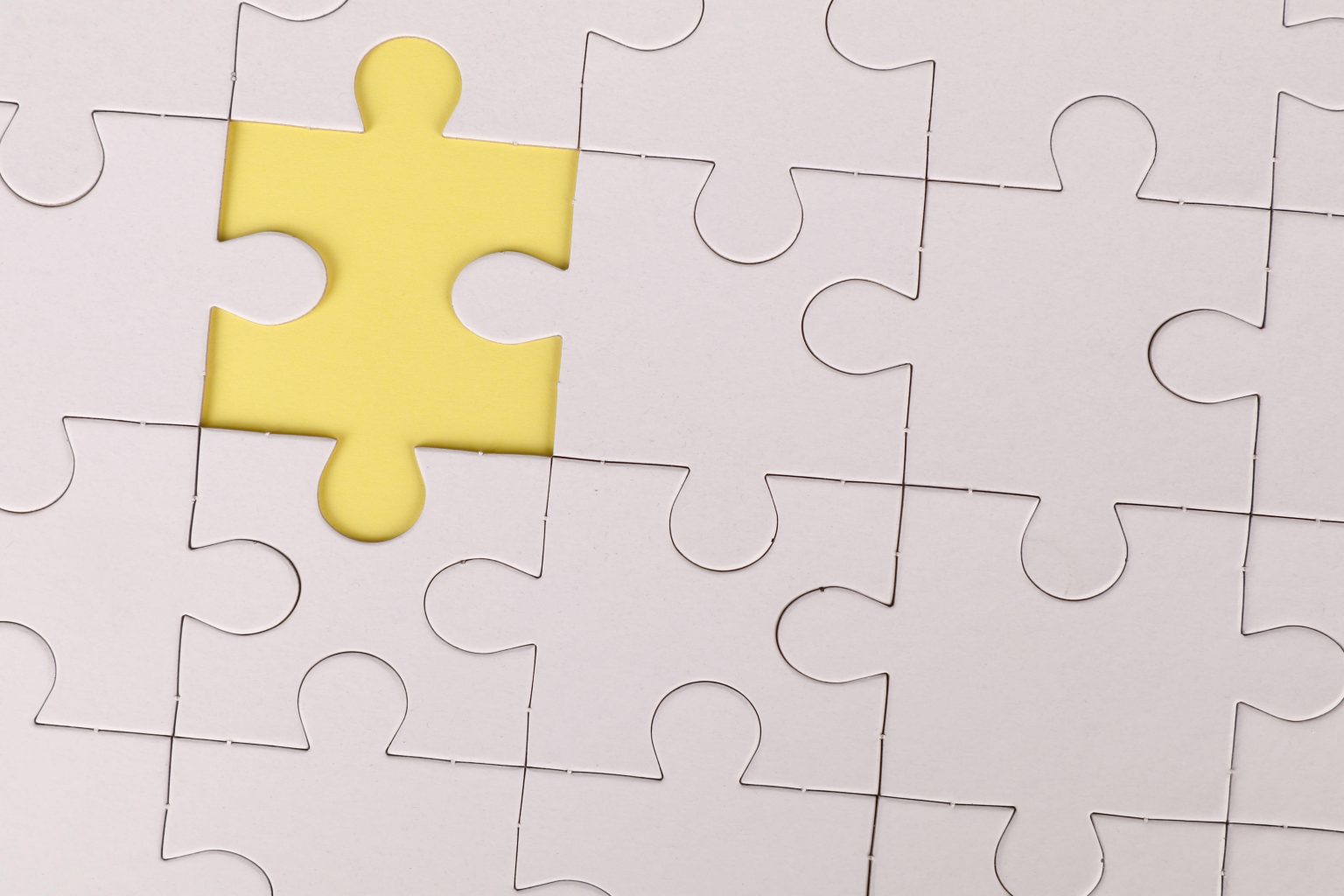 Weiße Puzzleteile mit gelber Lücke verdeutlichen strategische Lücke im Führungskräfte-Recruiting und betonen die Relevanz von Active Sourcing für schwer erreichbare Schlüsselpositionen.